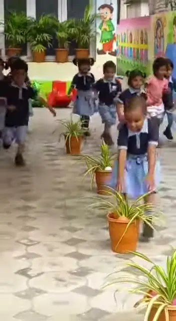 Children carrying potted plants across the courtyard